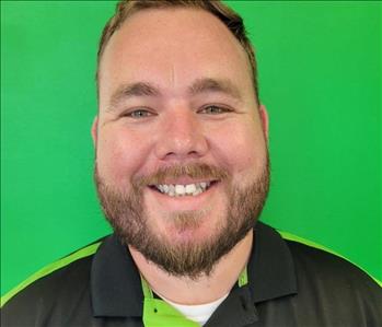 Man standing in front of a green background with SERVPRO shirt on.