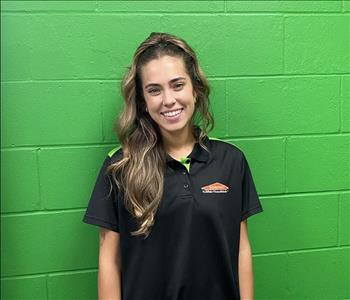 female employee standing in front of a green wall