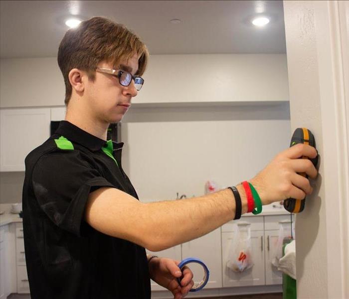 Production Technician monitoring moisture on a wall