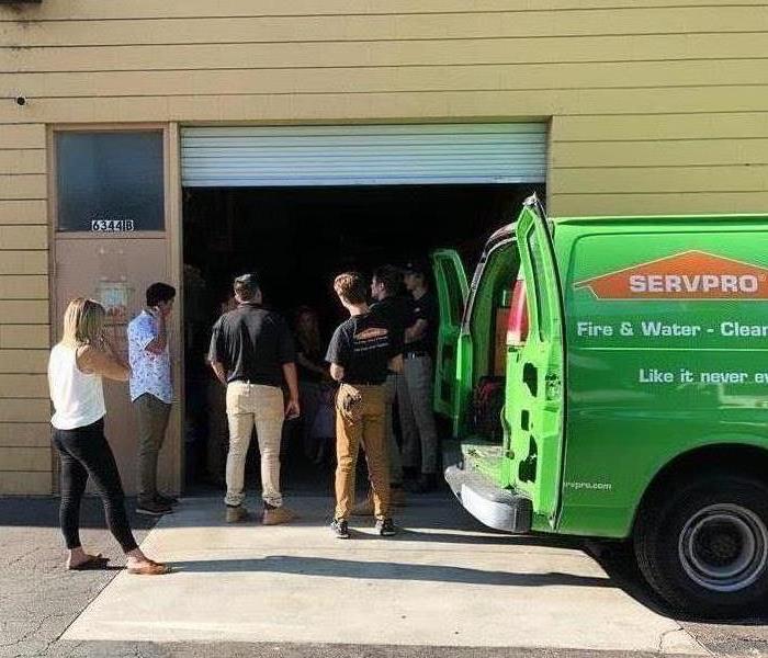 SERVPRO staff meeting outside, near green SERVPRO vehicle. 