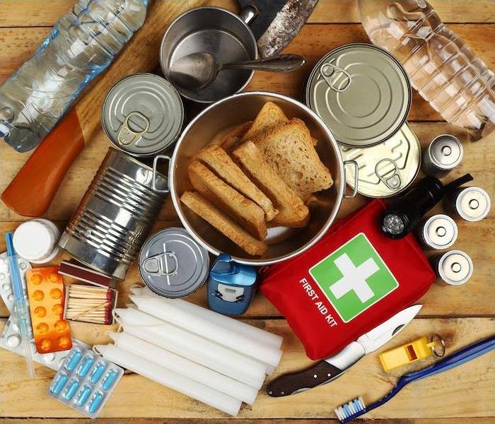 Emergency kit with canned food, water, first aid, flashlight, matches, candles, and other essentials