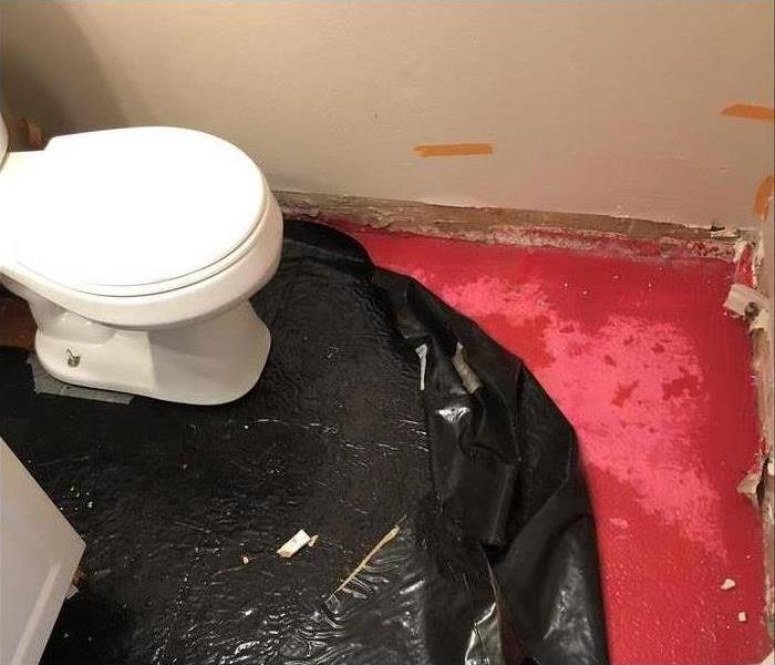 Toilet, black plastic bag on bathroom floor placed
